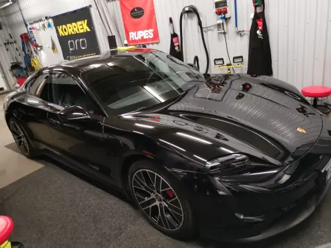 Musta Porsche edestä ja sivulta hallin valaistuksessa