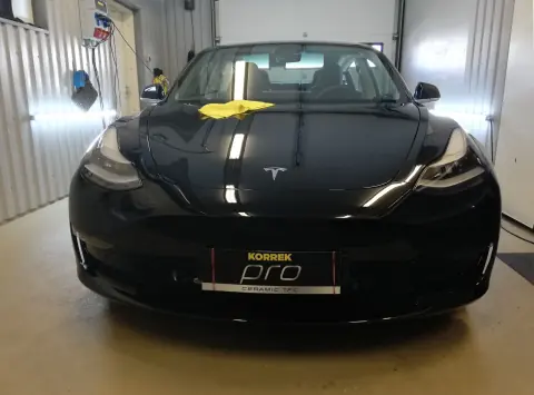 Musta Tesla edestä, konepellillä mikrokuituliina
