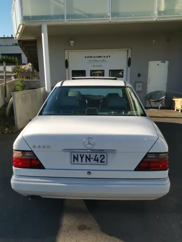 Valkoinen Mercedes-Benz takaa hallin ulkopuolella