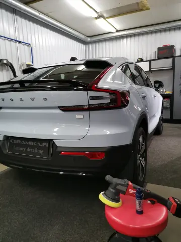 Valkoinen Volvo takaviistosta, vieressä hoitoaineita