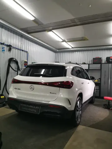 Valkoinen Mercedes-Benz katumaasturi takaviistosta hallin valaistuksessa