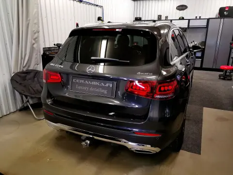 Musta Mercedes-Benz katumaasturi takaviistosta hallin valaistuksessa