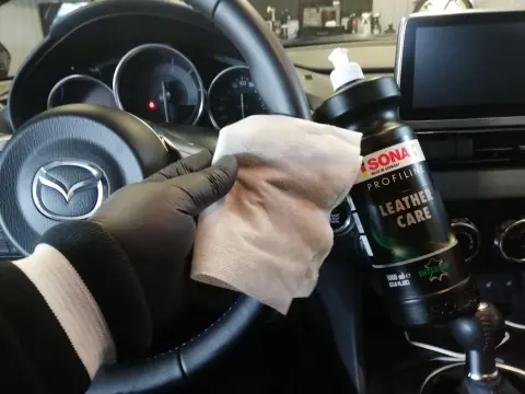 Nahkapinnan hoitoainepullo ja mikrokuituliina auton sisällä