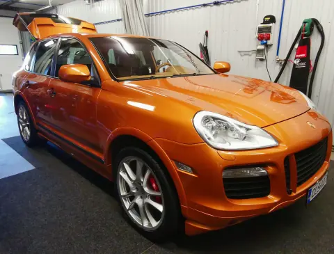 Oranssi Porsche katumaasturi edestä ja sivulta