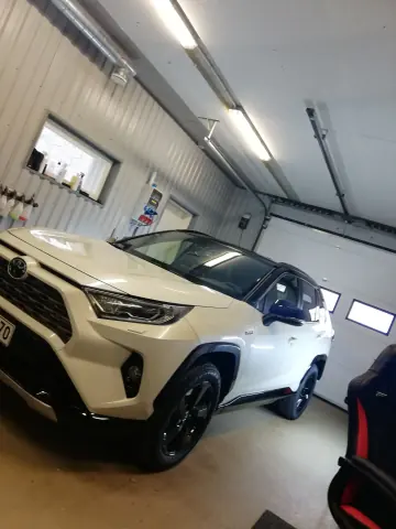 Valkoinen Toyota RAV4 edestä ja sivulta hallissa