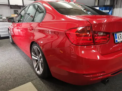Punaisen BMW:n kylki ja takaosa hallin valaistuksessa